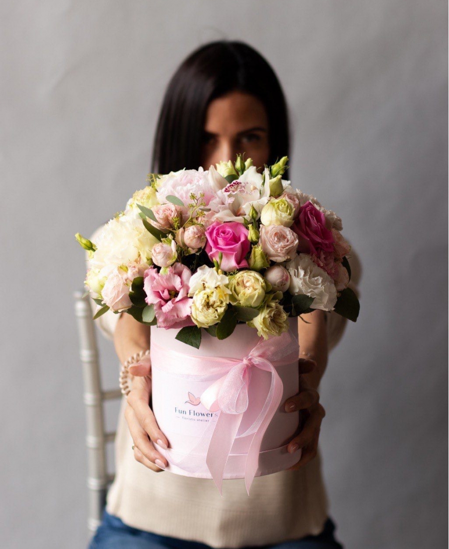 Flowers in a hatbox with roses and lisianthus in addition to peony varieties of roses